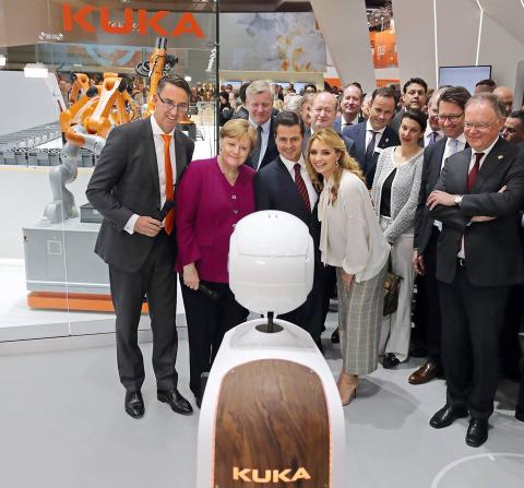 German Chancellor Angela Merkel observes robots at Hannover Messe. (Credit: KUKA)