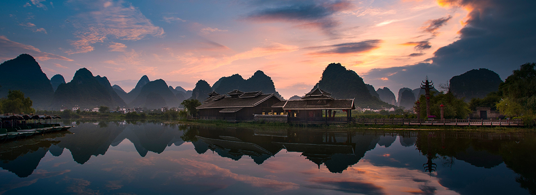 Waterfront building highlighting Asian architecture with mountains in the background.