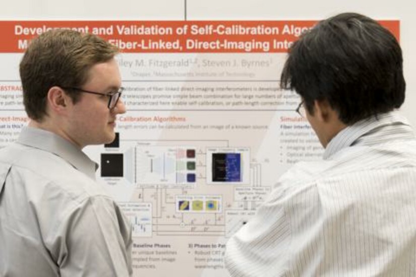Two students discuss a research poster at the Draper Scholar Research Symposium.