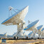 Array of large radio telescopes in a desert landscape under a clear blue sky.