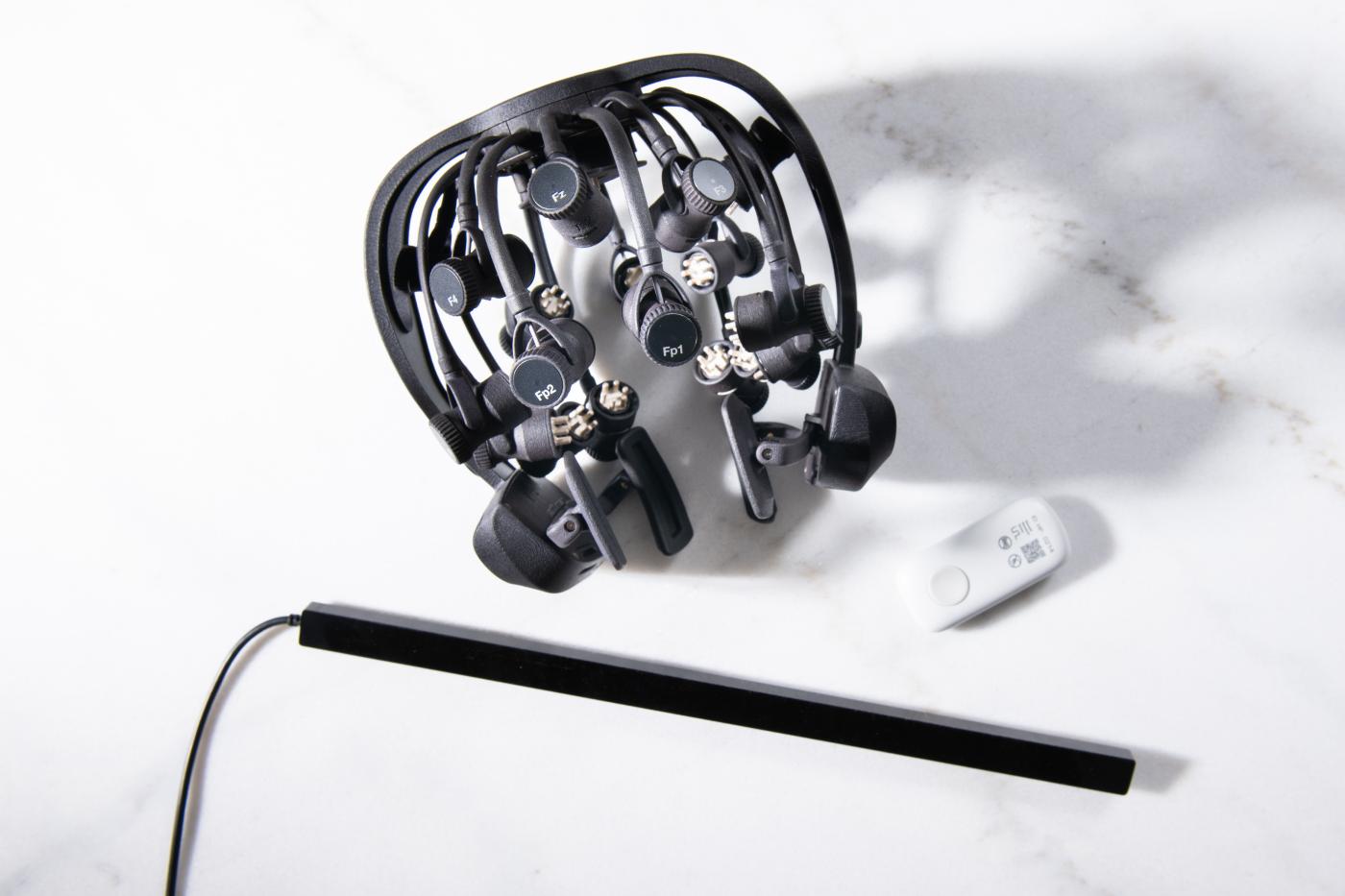 A device with arms that is placed on the head to sit at different areas. Small white protrusions are on the end of each arm