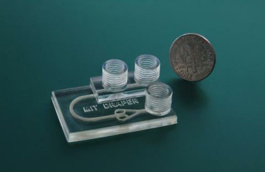 First-of-its-kind device for personalized immunotherapy, next to a coin.