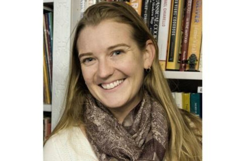 Kelly Sprehn, president of HFES New England, smiling in front of a bookshelf.