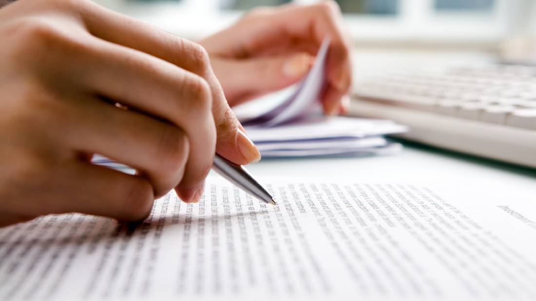person with pen over page of text