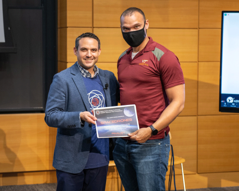 Dustin Martin of Draper congratulates Marco Peterson of SpaceDrones as a finalist at the COSMIC Pitch Competition during the Space Sector Market Conference. Credit: Draper.