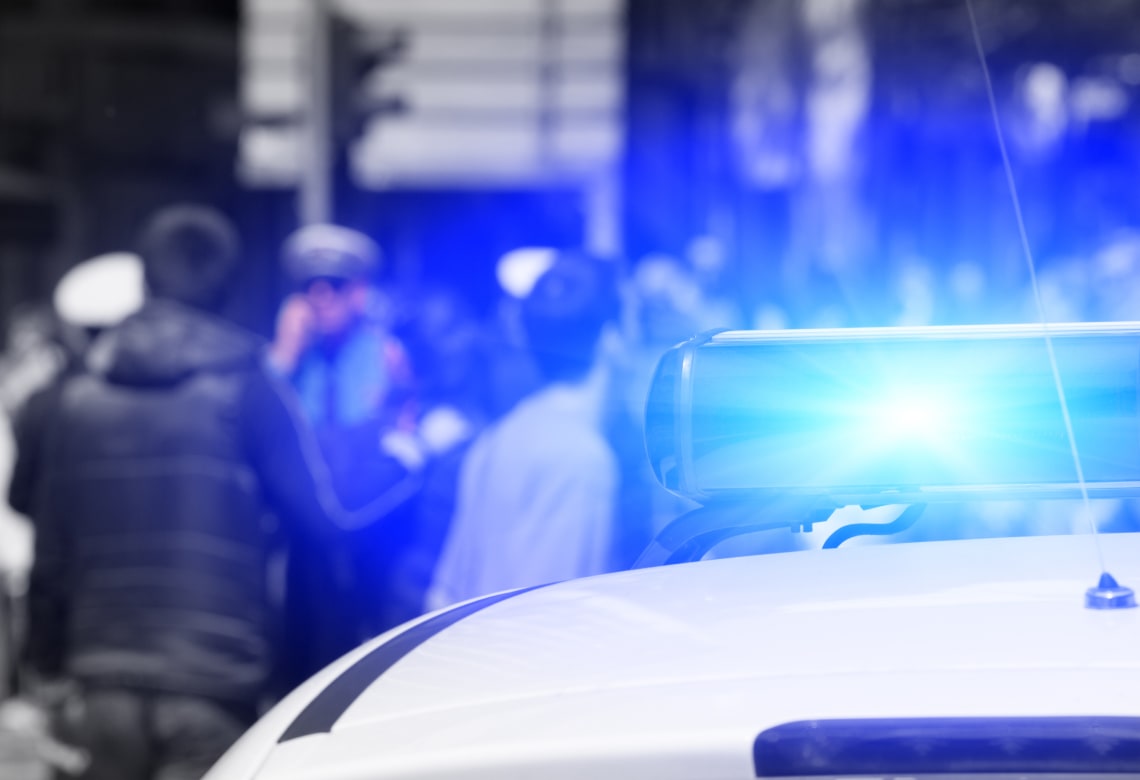Top of cop car, showing blue light. People in blurred background