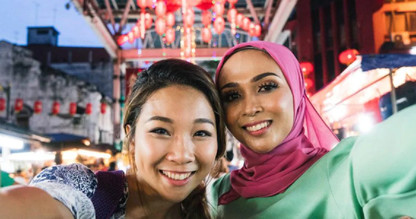 Two women taking a selfie in front of an Asian market.