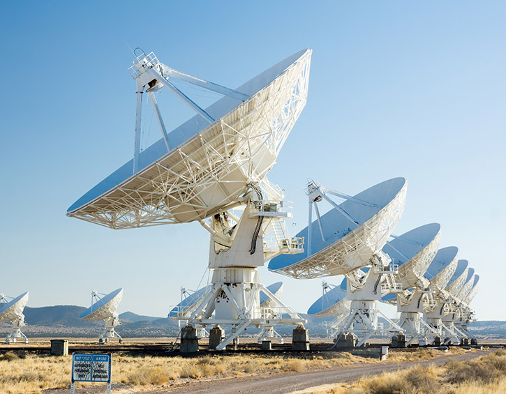 Array of large radio telescopes in a desert landscape under a clear blue sky.