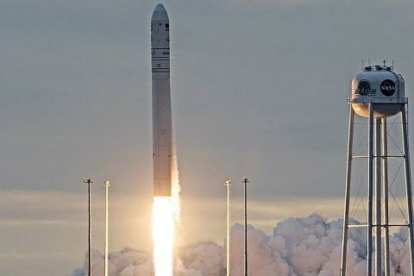 Rocket launching into the sky with NASA water tower in the background.