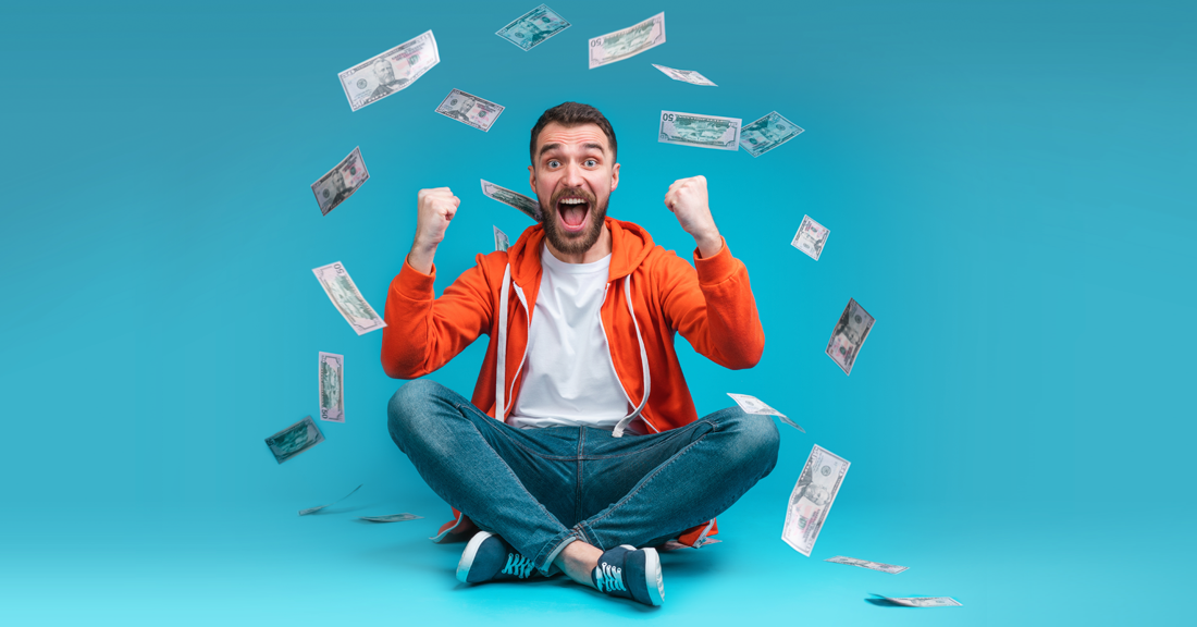 Guy smiling and sitting with money raining down on him