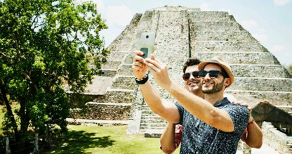 Two men taking a selfie in front of an ancient pyramid.