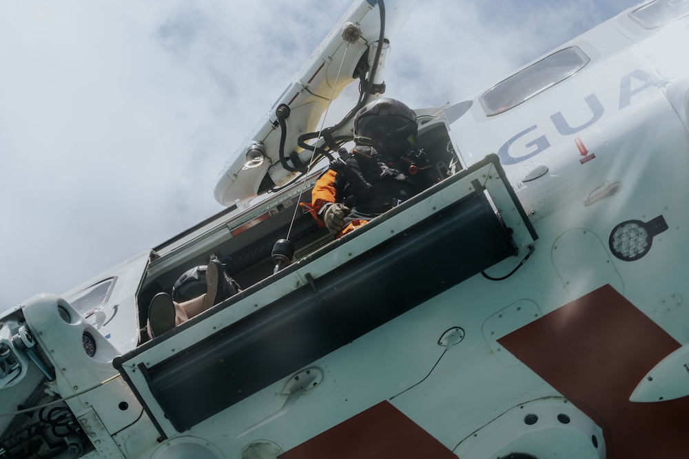Man hanging out the side of a helicopter