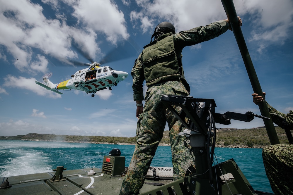 Man in boat watching a helicopter low above the water