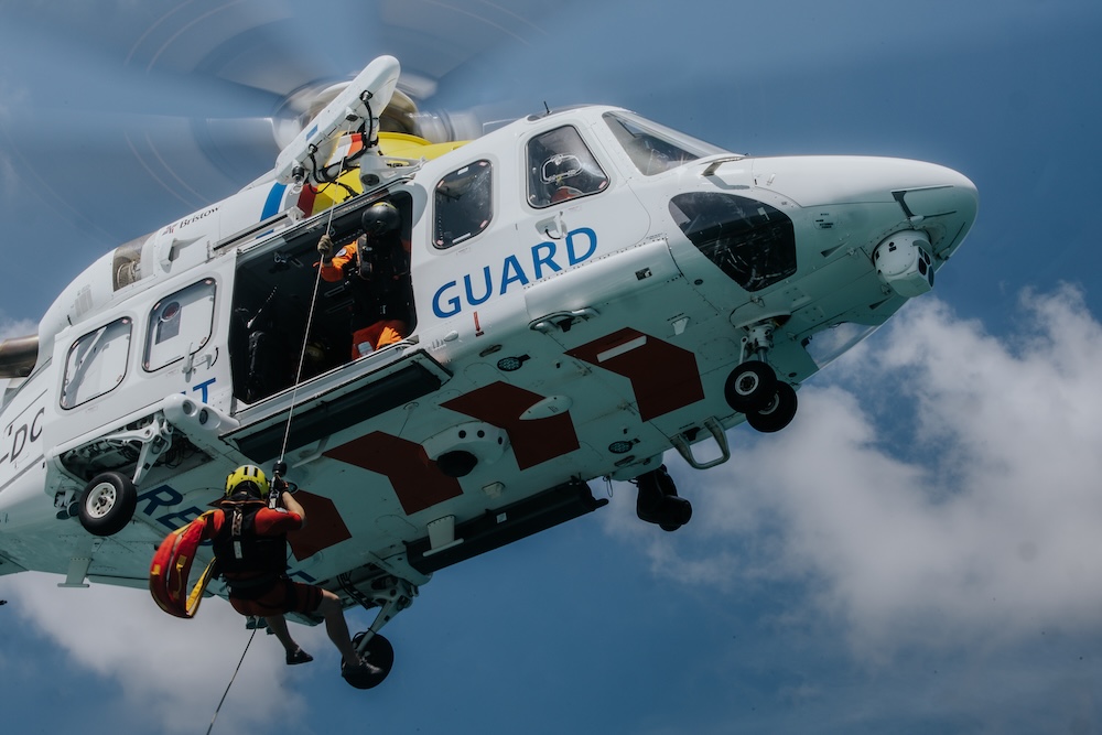 Helicopter with sidedoor open and man on a wire.