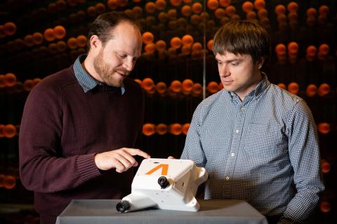 (L-R) Draper engineers Brett Streetman and Ted Steiner inspect the Draper multi-environment navigator, or DMEN. The DMEN system traveled as a payload on New Shepard’s 24th mission. Credit: Draper.