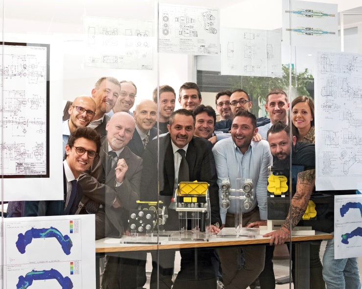 Employees posing for a group photo behind glass