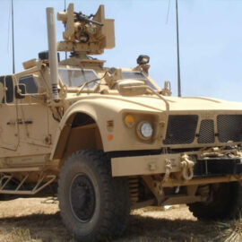 Military armored vehicle equipped with advanced weaponry and communication systems in a field.