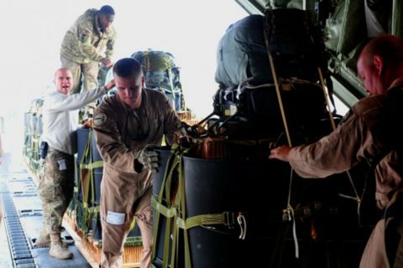 Military personnel prepare supplies for airdrop missions