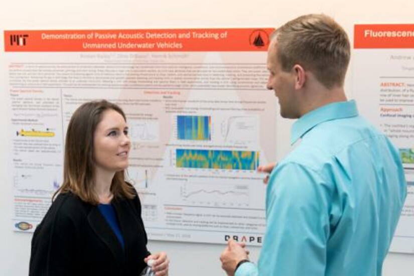 Two graduate students discuss research on acoustic detection at a Draper-supported event.