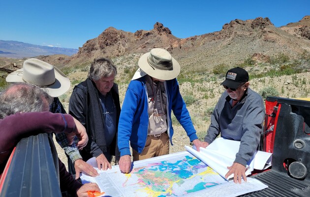 Men examining colorful topographical map on pickup truck bed
