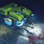 Underwater ROV exploring the ocean floor with robotic arms and bright lights.