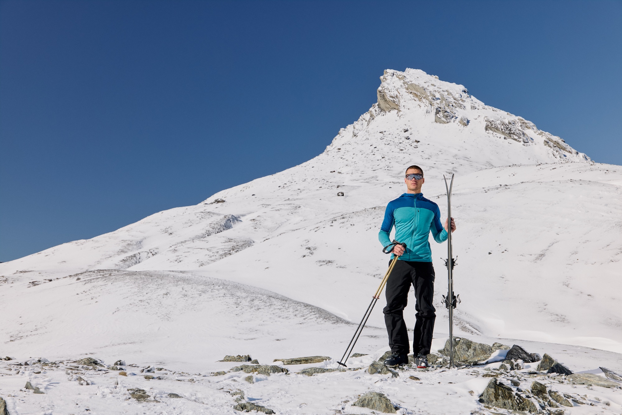 Man standing on mountain with skis and poles in hand