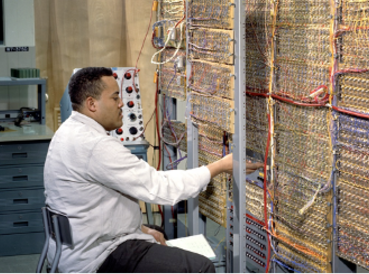 A technician works on a model of the Apollo guidance computer, built with integrated circuits.
