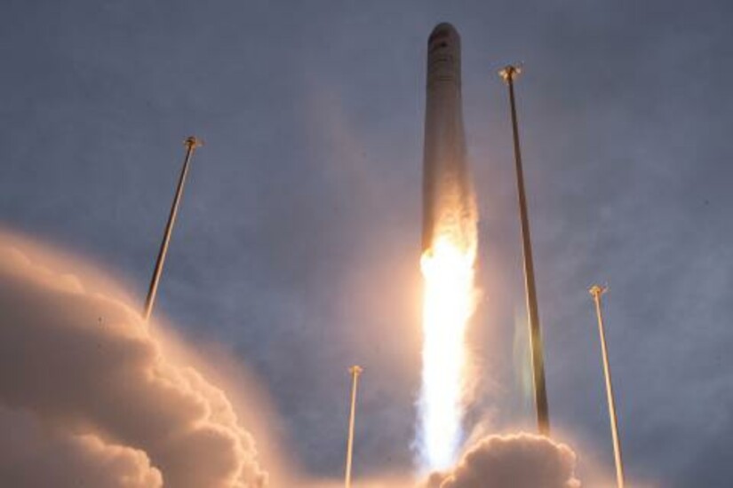 A rocket launches into the sky, leaving a trail of smoke and fire against a cloudy backdrop.