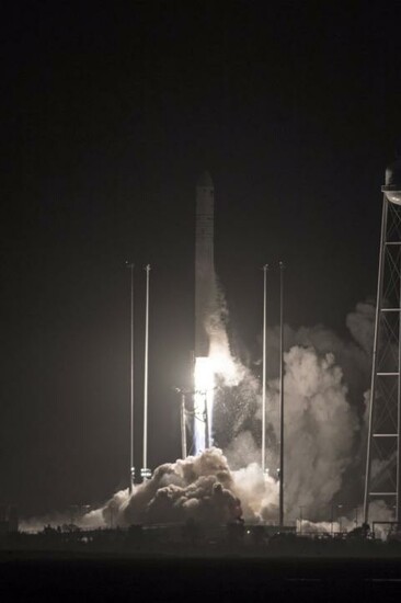 A rocket launches into the night sky, illuminating the surroundings with bright flames and smoke.
