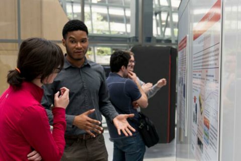 Draper Fellow Program alumni discussing research posters at a conference.