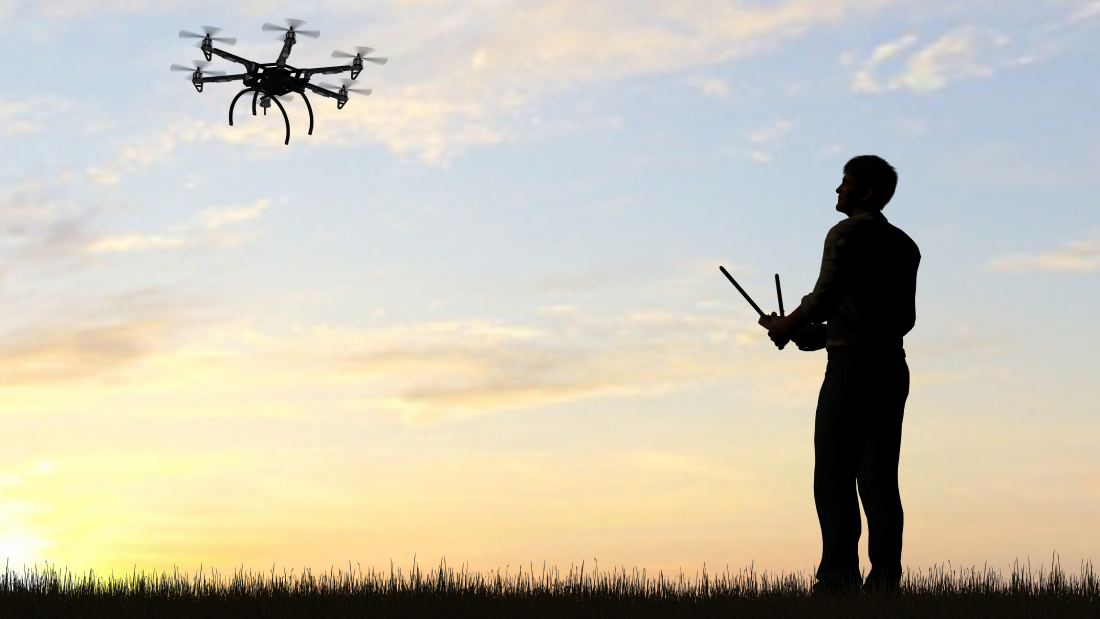Man on a field, flying drone