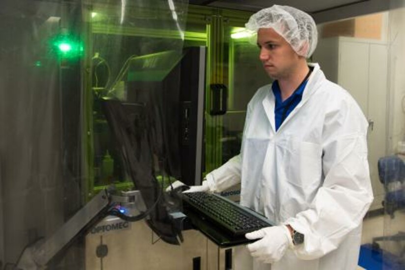 A technician operates a machine in a lab