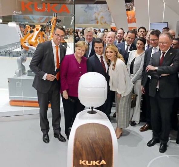 German Chancellor Angela Merkel observes robots at Hannover Messe with a group of attendees.