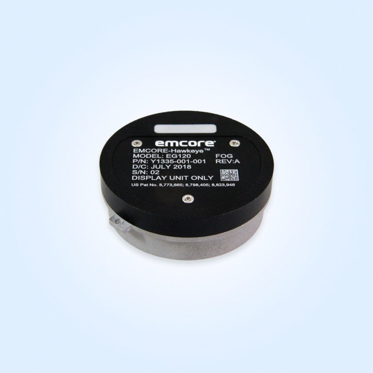 A cylindrical device with a black top and silver bottom. The label reads: EMCORE-Hawkeye Model EG120 FOG display unit with part number Y1335-001-001, dated July 2018.