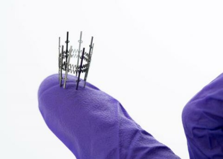 A gloved hand holding a pediatric heart valve stent