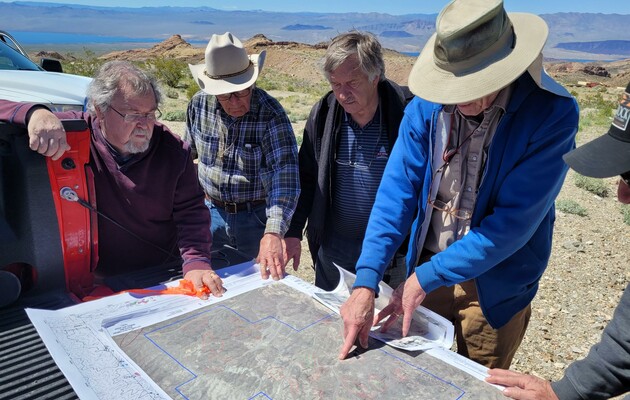 Men examining general site layout map on pickup truck bed