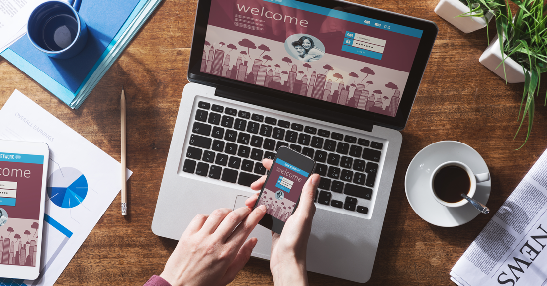 Laptop open with welcome page open, person holding phone with welcome screen open
