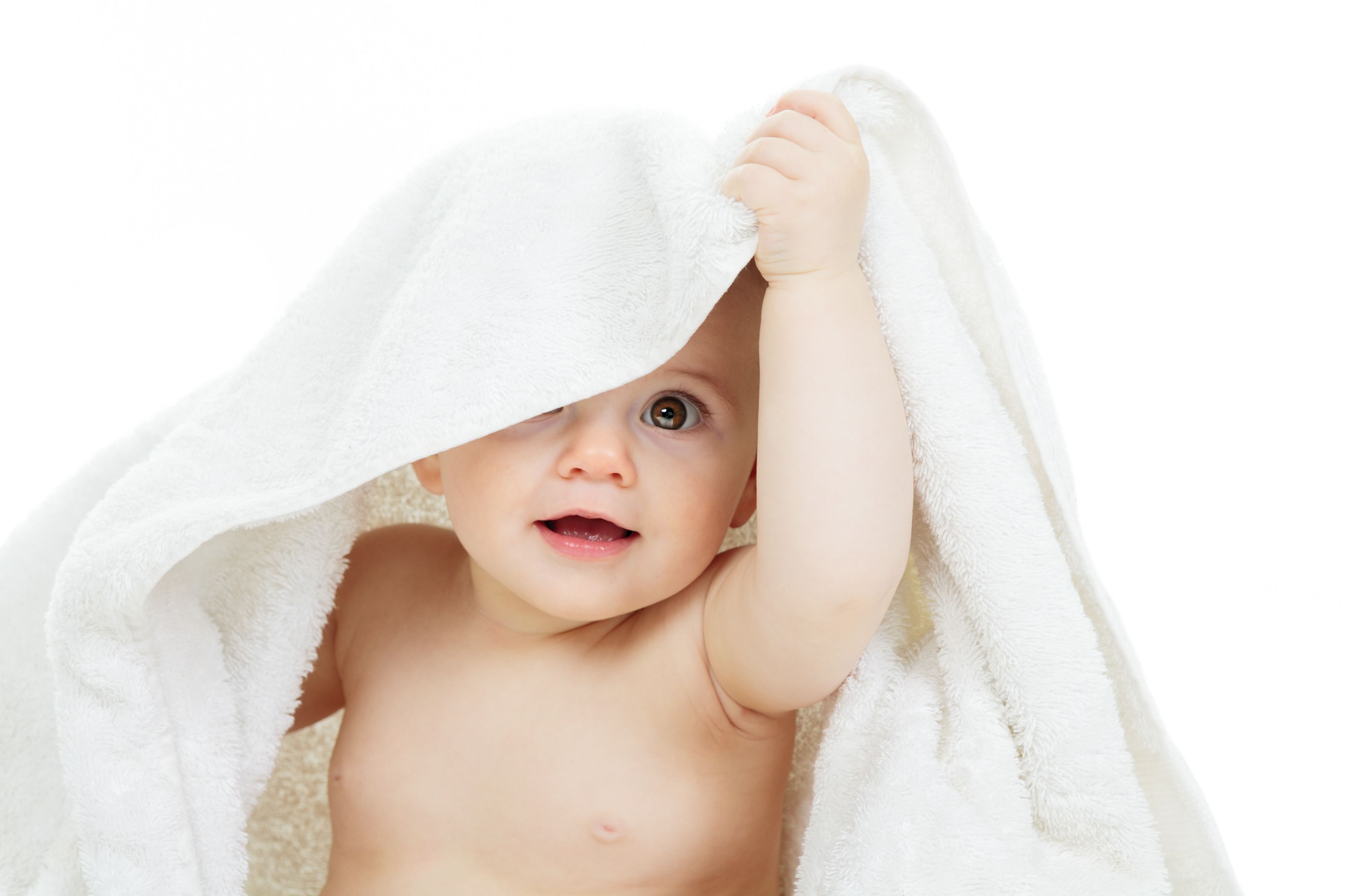 A baby peeking out from under a towel